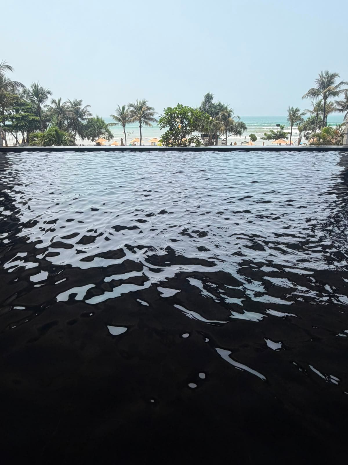 The mirror-black infinity pool, running to the beach